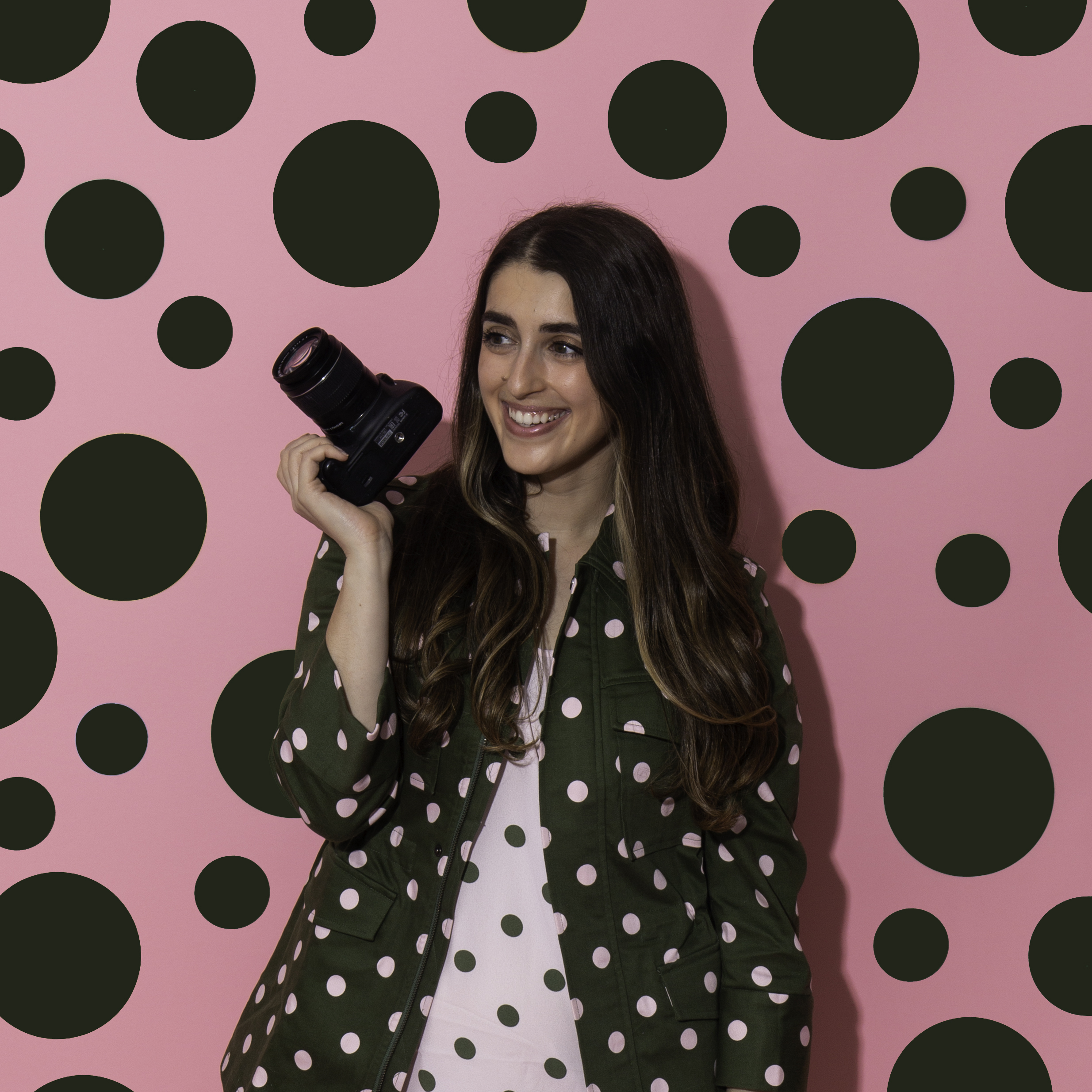 alisha holding camera in front of polka dot background