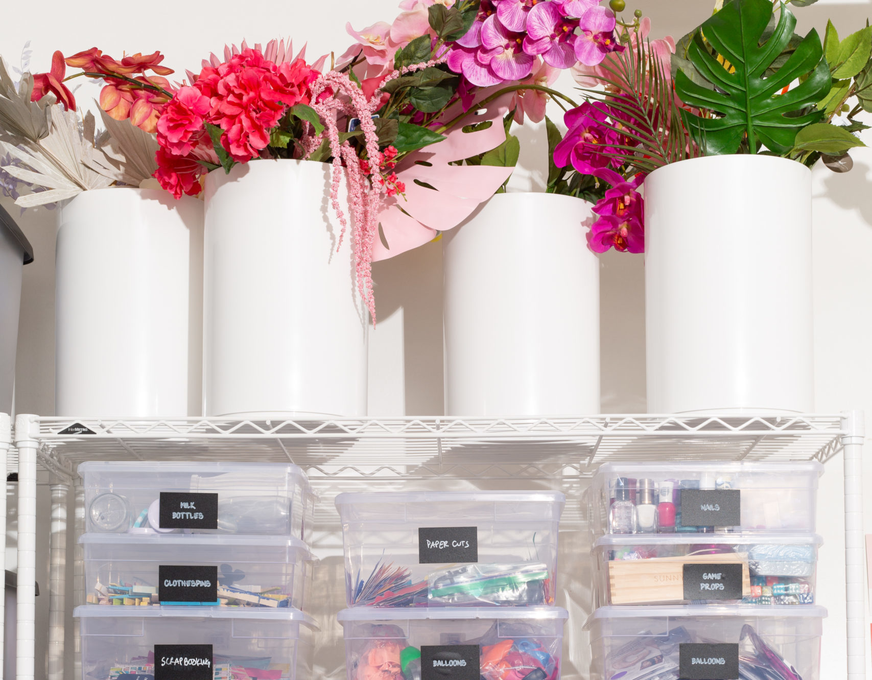 shelf of organized bins featuring white trash bins used as storage of florals
