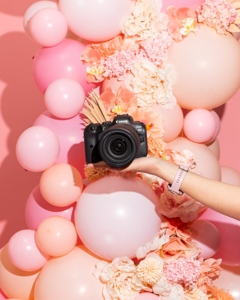 hand holding canon eos r6 camera in front of pink balloon installation