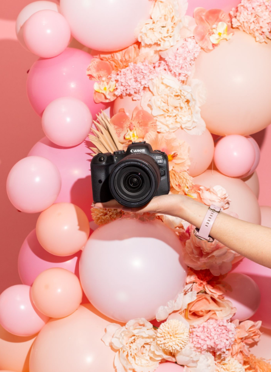 Hand holding camera against pink background