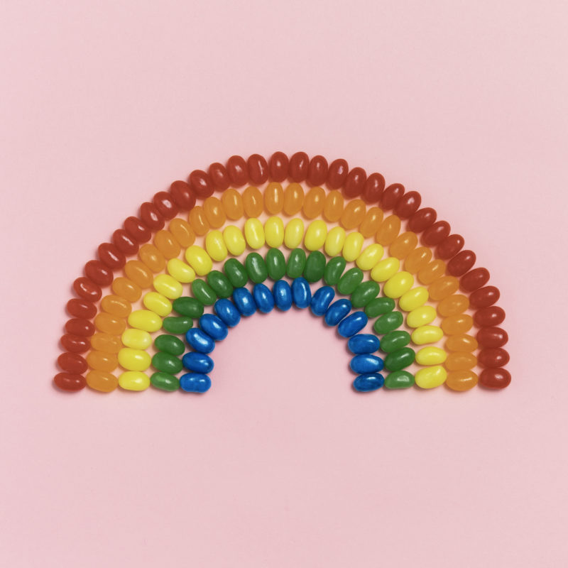 rainbow made out of colored candy on pink background