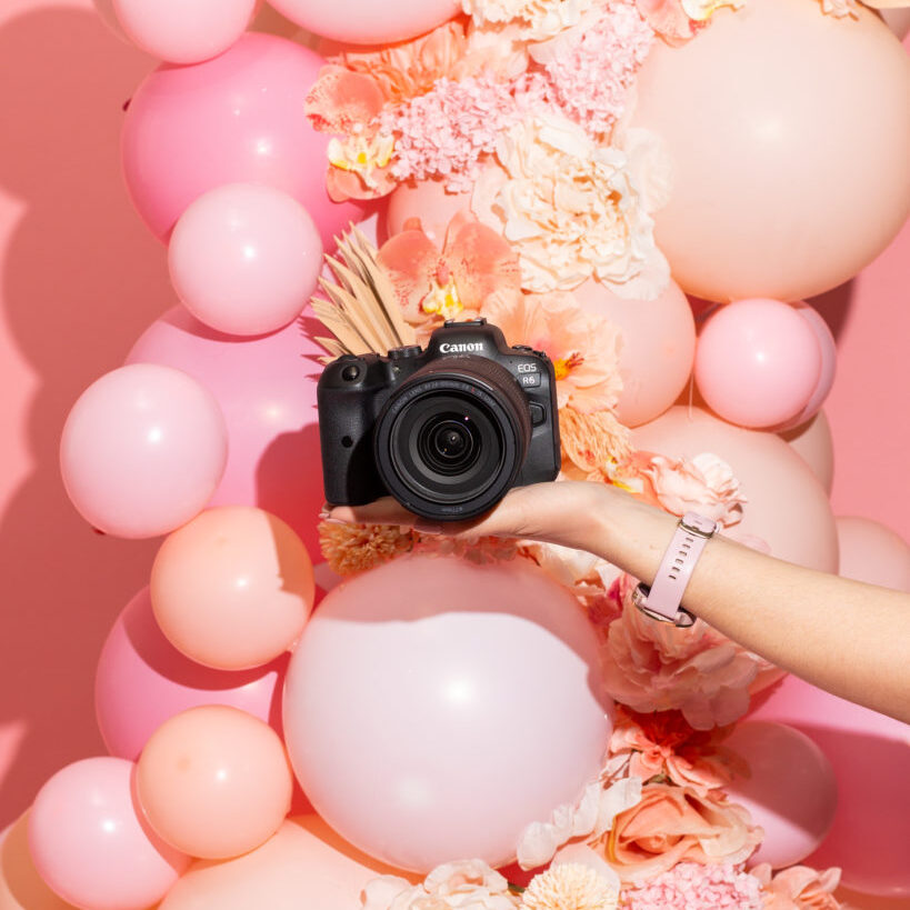 hand holding canon eos r6 camera in front of pink balloon installation